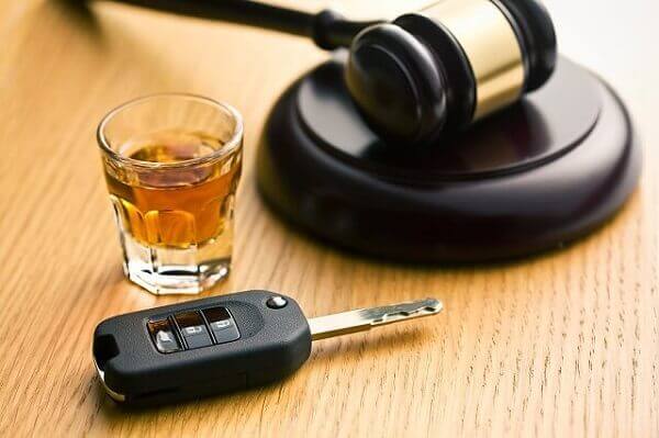 A carkey, gavel and a drinking shot glass.